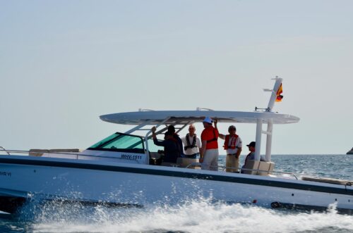 Gruppe von Trainingsteilnehmern mit Schwimmwesten auf einem fahrenden Motorboot auf dem Mittelmeer bei Port Calanova